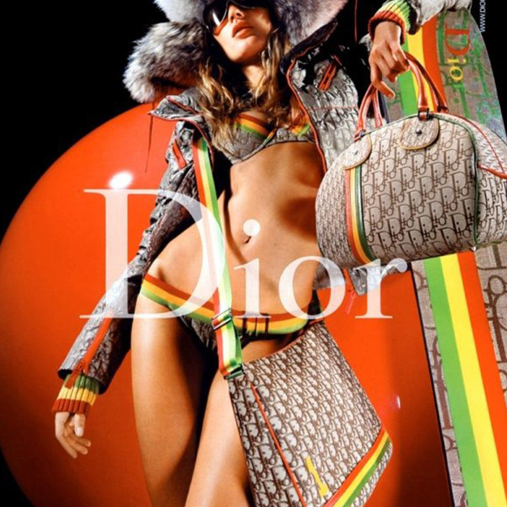 Christian Dior ad campaign Rasta Boston Bag by John Gallian for Dior. Beige and light brown Diorissimo canvas with silver-tone hardware, domed feet, 2 red leather rolled top handles, zipper pulls and end tab and red, yellow and green leather piping and tri-color leather front stripe. Made in Italy