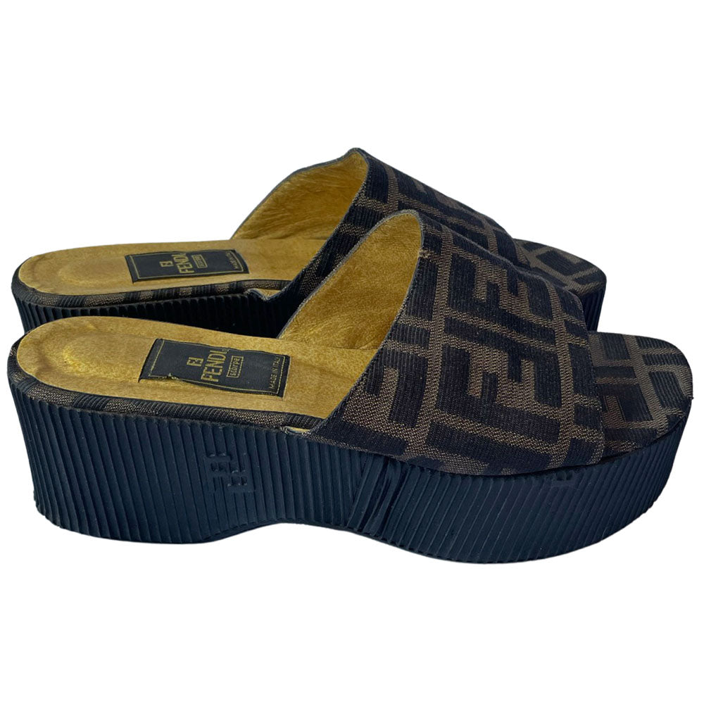 Fendi brown Zucca print fabric upper slip-on open toe slides with 2.5” black ribbed edge platform with small heel. Leather insoles with zucca fabric at inner sole toe, Fendi logo on inner sole, FF logos imprinted at outer platform. Made in Italy.