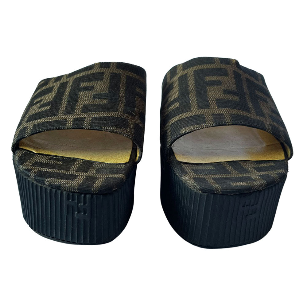 Fendi brown Zucca print fabric upper slip-on open toe slides with 2.5” black ribbed edge platform with small heel. Leather insoles with zucca fabric at inner sole toe, Fendi logo on inner sole, FF logos imprinted at outer platform. Made in Italy.