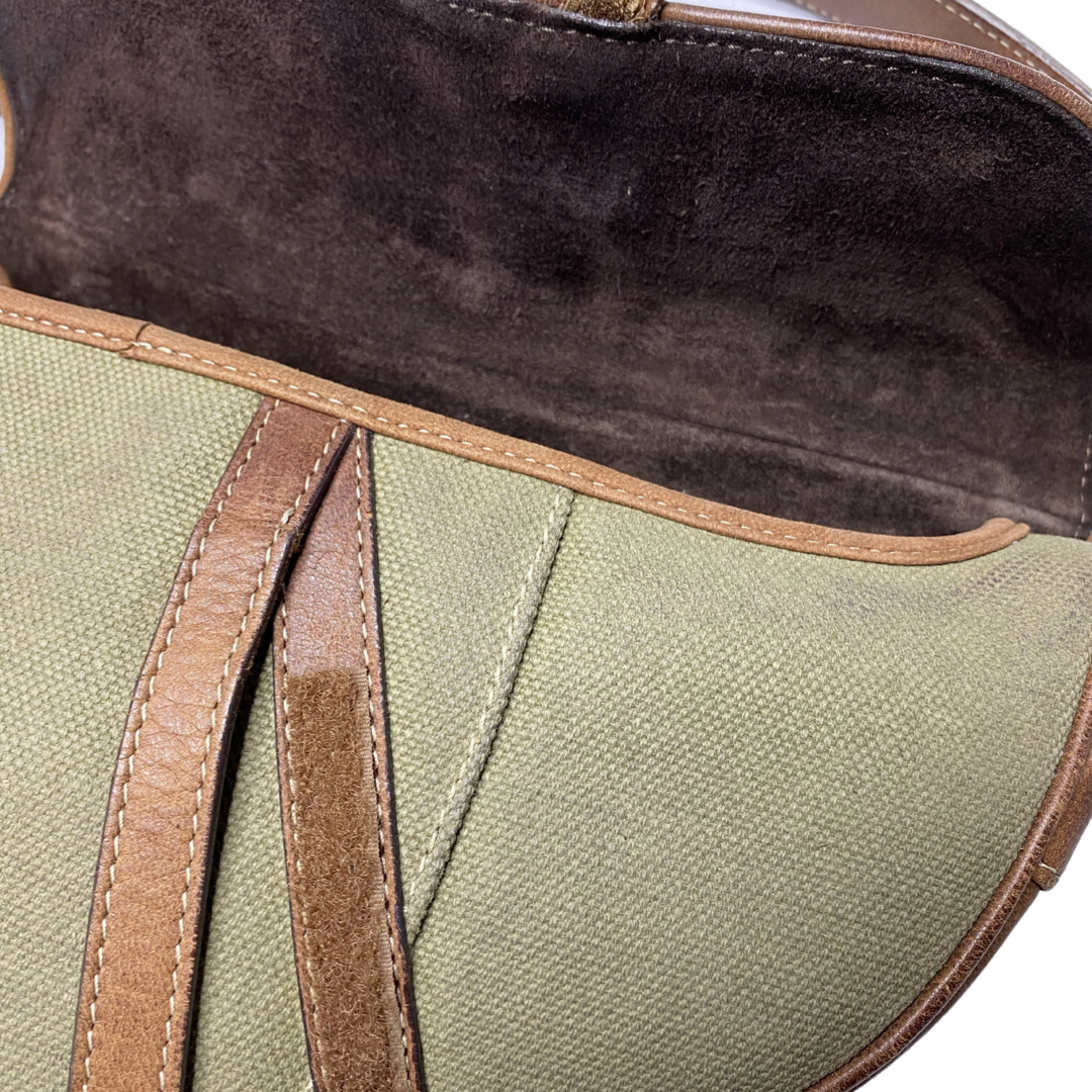 Christian Dior khaki canvas saddle bag by John Galliano for Dior 2002 with burnished gold-tone hardware, brown leather accent. Single flat top leather handle with CD logo adornments at each side. Velcro at flap closure with feature gold-tone D logo. Rear single slip pocket. Black/grey logo textile lined with zip pocket. Made in Italy