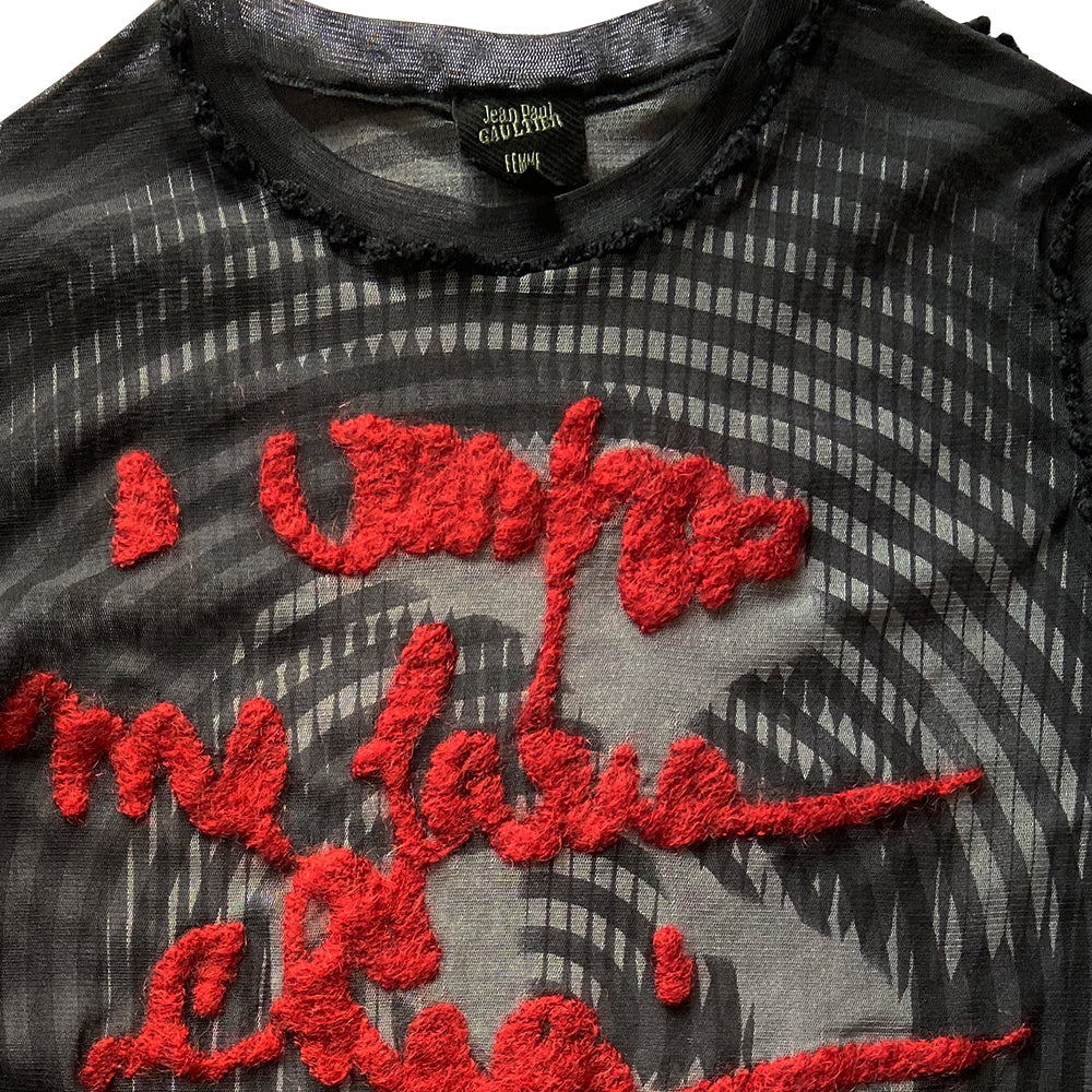 Jean Paul Gaultier Femme rare optical illusion long sleeve mesh top, AW 2001 featuring classic film icon Marlene Dietrich on front and back with red mohair front embroidered script writing and along one sleeve, black boucle accent trim on seams and neckline. Tag size: 40. Made in Japan