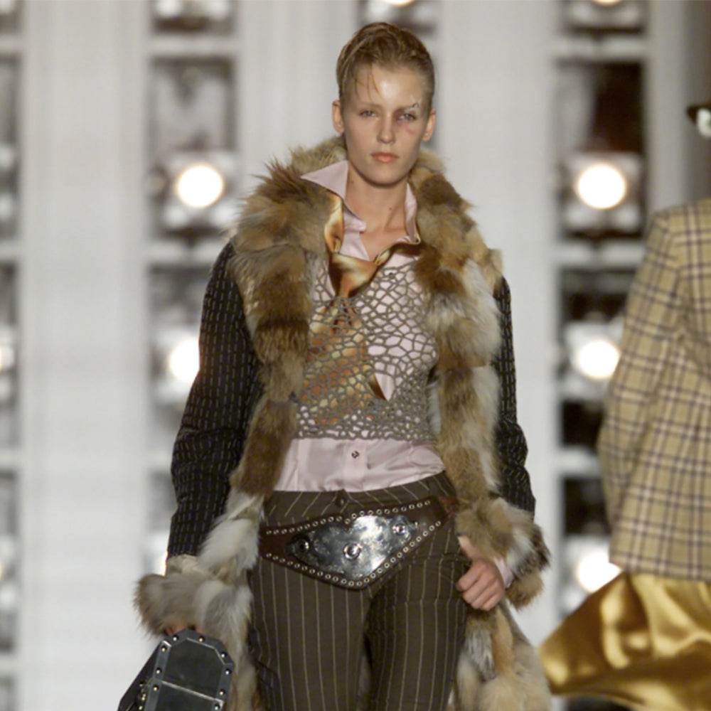 Christian Dior Championship Belt from fall 2001 RTW runway collection by John Galliano. Black leather belt with eyelets surrounding the large embossed silver-tone engraved metal plate with CD logo at center. Leather strands connect to end pieces with silver-tone CD engraved buckle with 6 adjustment holes. Made in Italy