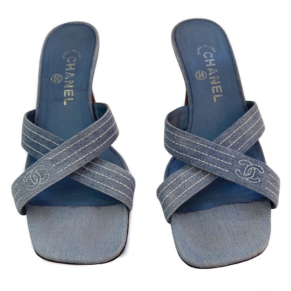 Chanel Blue Denim Criss Cross Slide Heels slip on style with criss cross denim and open toe with white accent stitching and CC logo, tan leather soles and wood heels Very good condition overall. Material: Denim upper, leather inner sole, leather bottom sole Color: light blue Size: 39 Made in Italy