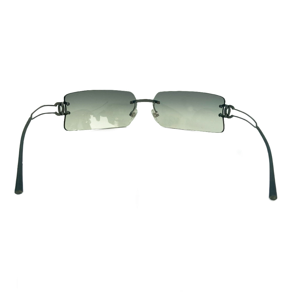Chanel rectangular rimless sunglasses with gray gradient lenses, double wire side arms and CC metal logo at sides. Red cleaning cloth and white hard case included