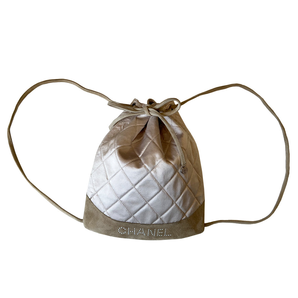 Chanel quilted satin soft backpack by Karl Lagerfeld for Chanel 2001 with suede straps and suede drawstring closure, silver-tone Chanel stamped tips. Embedded faux pearls spell-out CHANEL on exterior suede. Satin interior with single slip pocket. Date code tag attached. Periwinkle satin with tan suede. Made in France