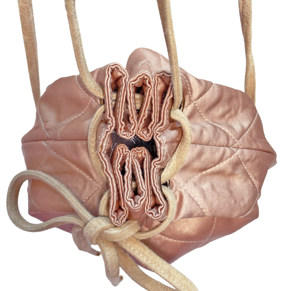 Chanel pink quilted satin and tan suede soft backpack by Karl Lagerfeld for Chanel 2001 with suede drawstring closure, silver-tone Chanel stamped tips and suede straps. Embedded faux pearls spell-out CHANEL embellishment on exterior suede satin interior with single slip pocket. Folds down flat. Made in France