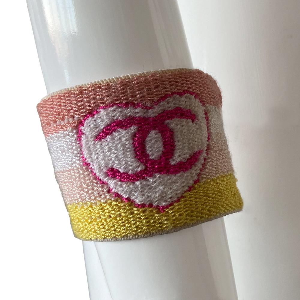 Chanel Sport heart and star sweatband wristband by Karl Lagerfeld for Chanel, cruise collection 2004 cruise. 4 color pastel striped elasticized terry knit sport wristband featuring fuchsia CC logo heart and star Color: Peach, white, pastel pink, yellow stripes, fuchsia heart and star logo