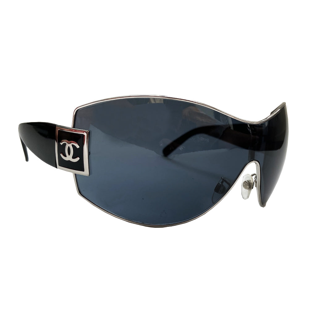 Chanel Oversized Shield Sunglasses with oversized lens surrounded by silver-tone metal frame, wide arms, square CC silver logo at sides that wrap on to the lens Condition: Excellent, no scratches on lens. Main Color: Black with black lens Case and dust cover included. Made in Italy.