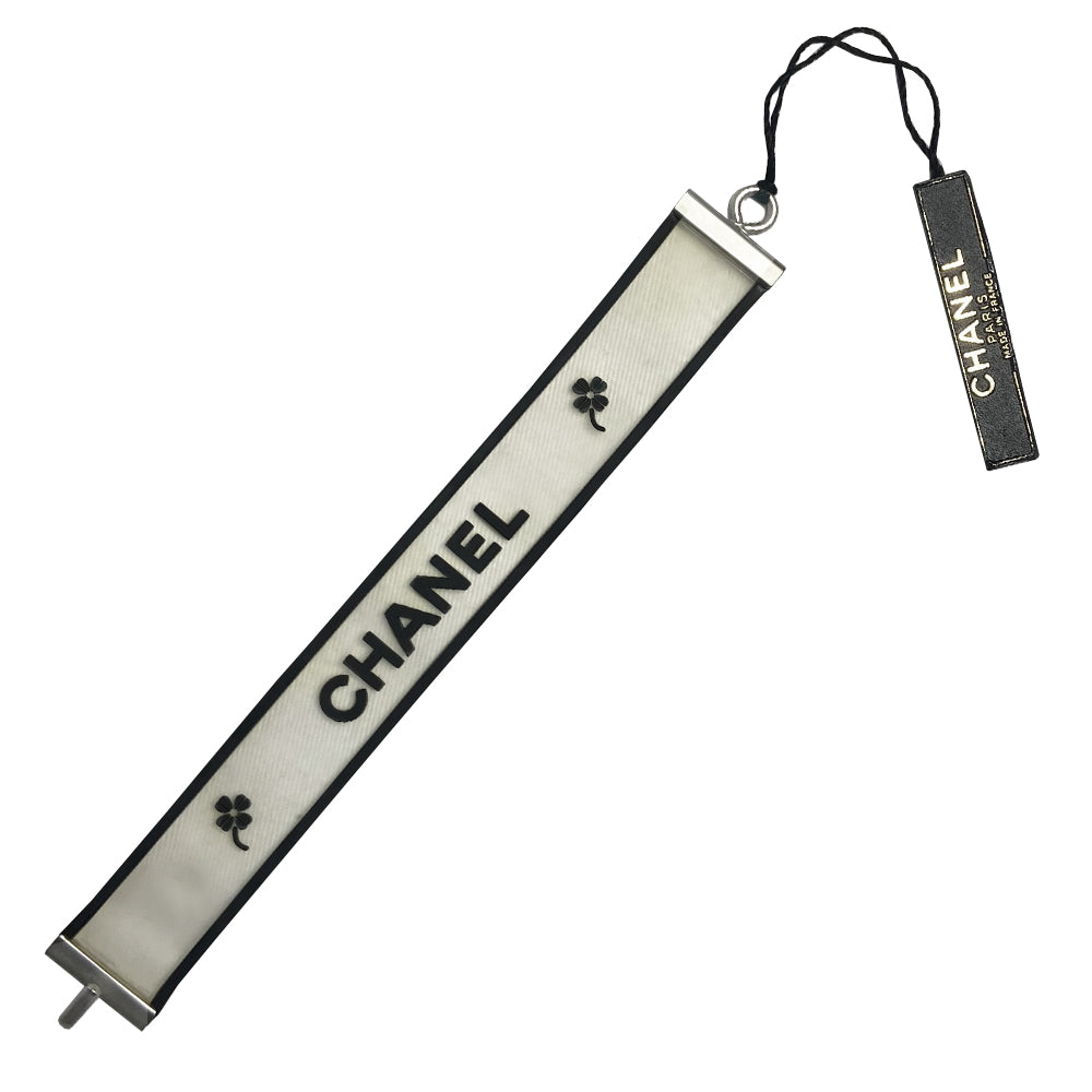 Chanel rubber bracelet by Karl Lagerfeld for Chanel, Autumn 2001 with translucent with black edges tinted rubber bracelet with CHANEL printed out and 2 clovers at each end in black. Silver-tone end caps and hook closure, Chanel hallmark makers mark stamp. Made in France