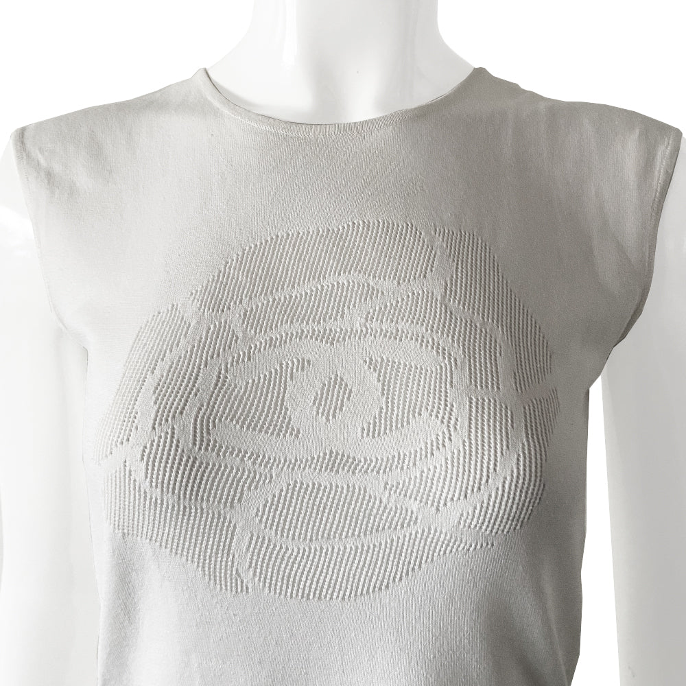 Chanel logo camellia sleeveless knit top in cream color with Interlocking CC logo centered within the signature camellia woven into fabric. Sleeveless with rounded neckline with ribbed edging. Fine rib knit of 100% cotton. Delicate pleats with fine crochet detail at hem. Size: FR 36
