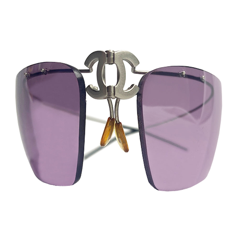 Chanel CC logo folding rimless wrap sunglasses by Karl Lagerfeld for Chanel, 1990’s. Continuous silver-tone wrap around wire top frame and arms attached to purple tinted lenses with center folding hinge at CC logo nose bridge. Model: 4032 Chanel soft case included. Made in Italy