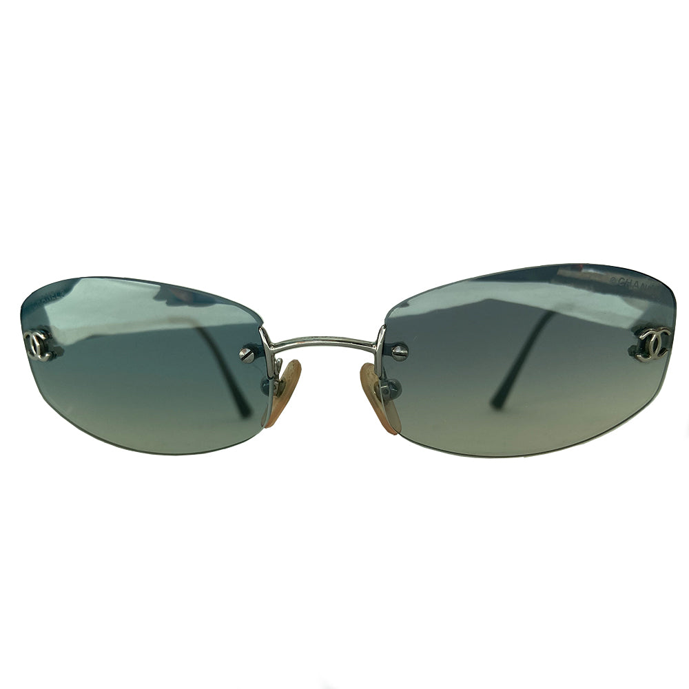 Chanel blue gradient lens frameless logo sunglasses with rectangular shaped gradient blue rimless lenses and CC logo in silver on each lens. Silver-tone arms with CC logo at the tip of each arm. Hard case included. Made in Italy