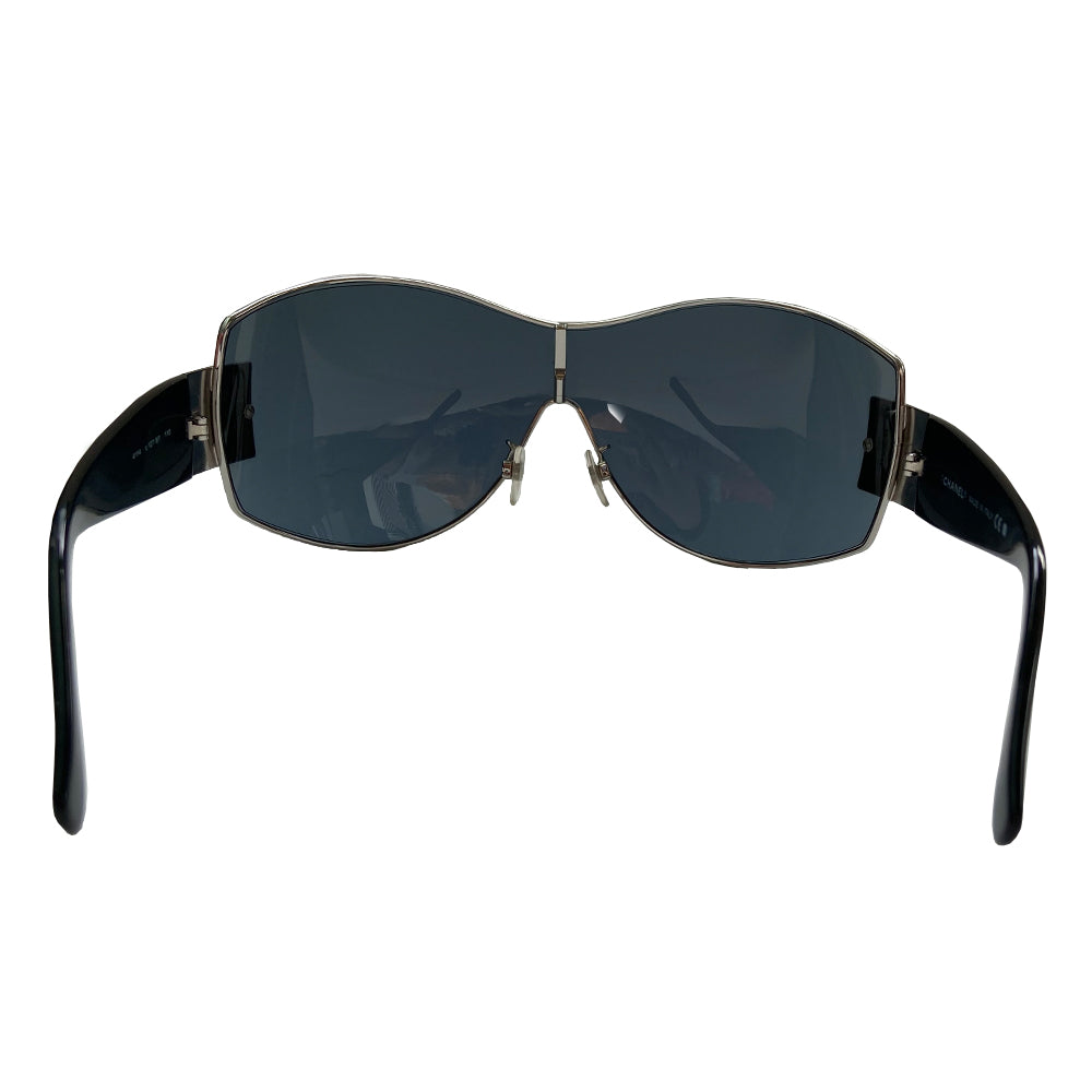 Chanel Oversized Shield Sunglasses with oversized lens surrounded by silver-tone metal frame, wide arms, square CC silver logo at sides that wrap on to the lens Condition: Excellent, no scratches on lens. Main Color: Black with black lens