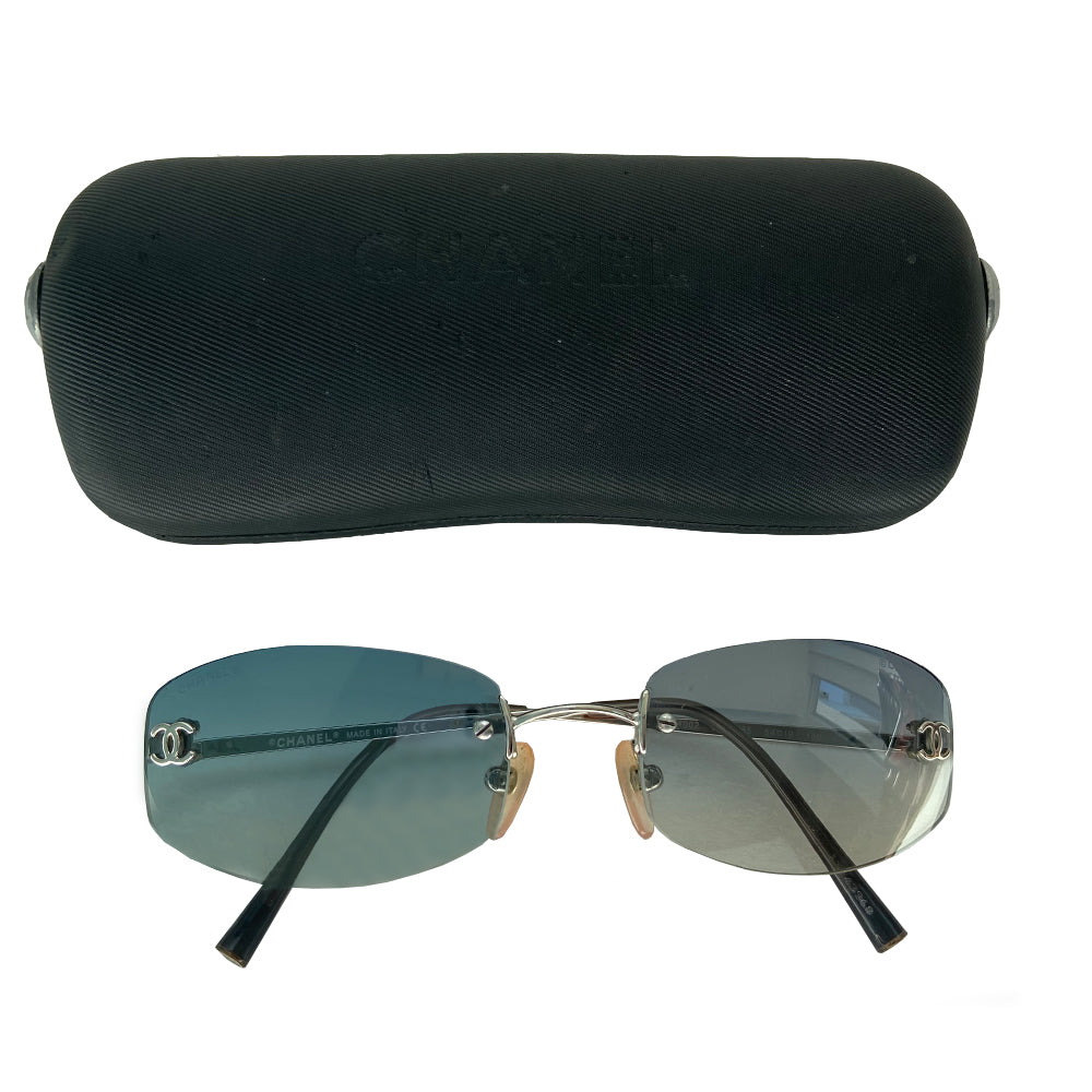 Chanel blue gradient lens frameless logo sunglasses with rectangular shaped gradient blue rimless lenses and CC logo in silver on each lens. Silver-tone arms with CC logo at the tip of each arm. Hard case included. Made in Italy