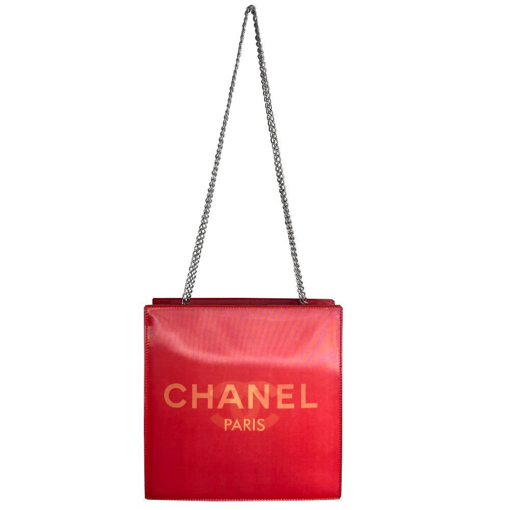 Chanel rectangular vinyl shoulder bag by Karl Lagerfeld for Chanel, 2000 with silver-tone double chain shoulder strap and lenticular/holograph design that flip flops between gold-tone interlocking CC logo and CHANEL Paris. Open top with vinyl interior and one zippered pocket. Made in France
