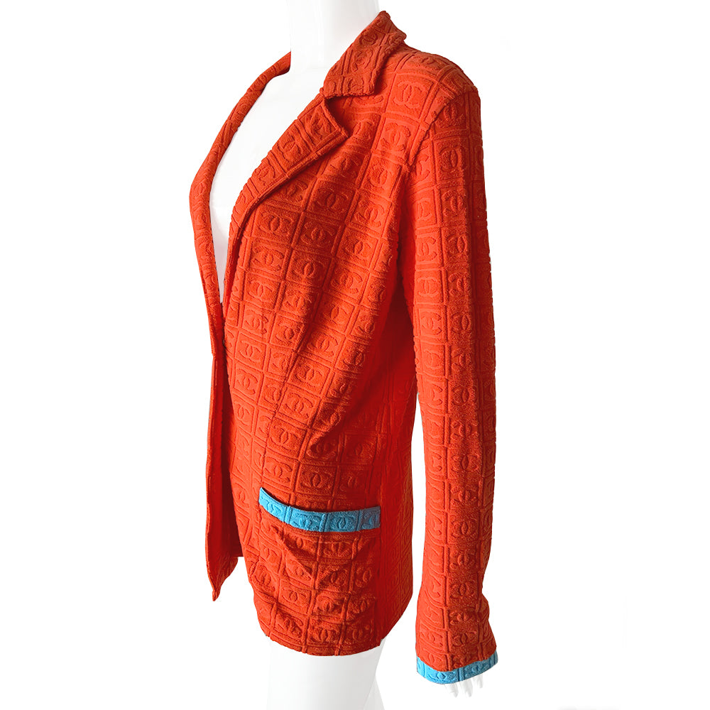 Chanel monogram terrycloth blazer by Karl Lagerfeld for Chanel S/S 2002 with long sleeves, all over boxed CC logo pattern, notched lapel, single logo silver-tone front snap button closure and 2 front patch pockets. Tangerine orange with turquoise accent. Made in France