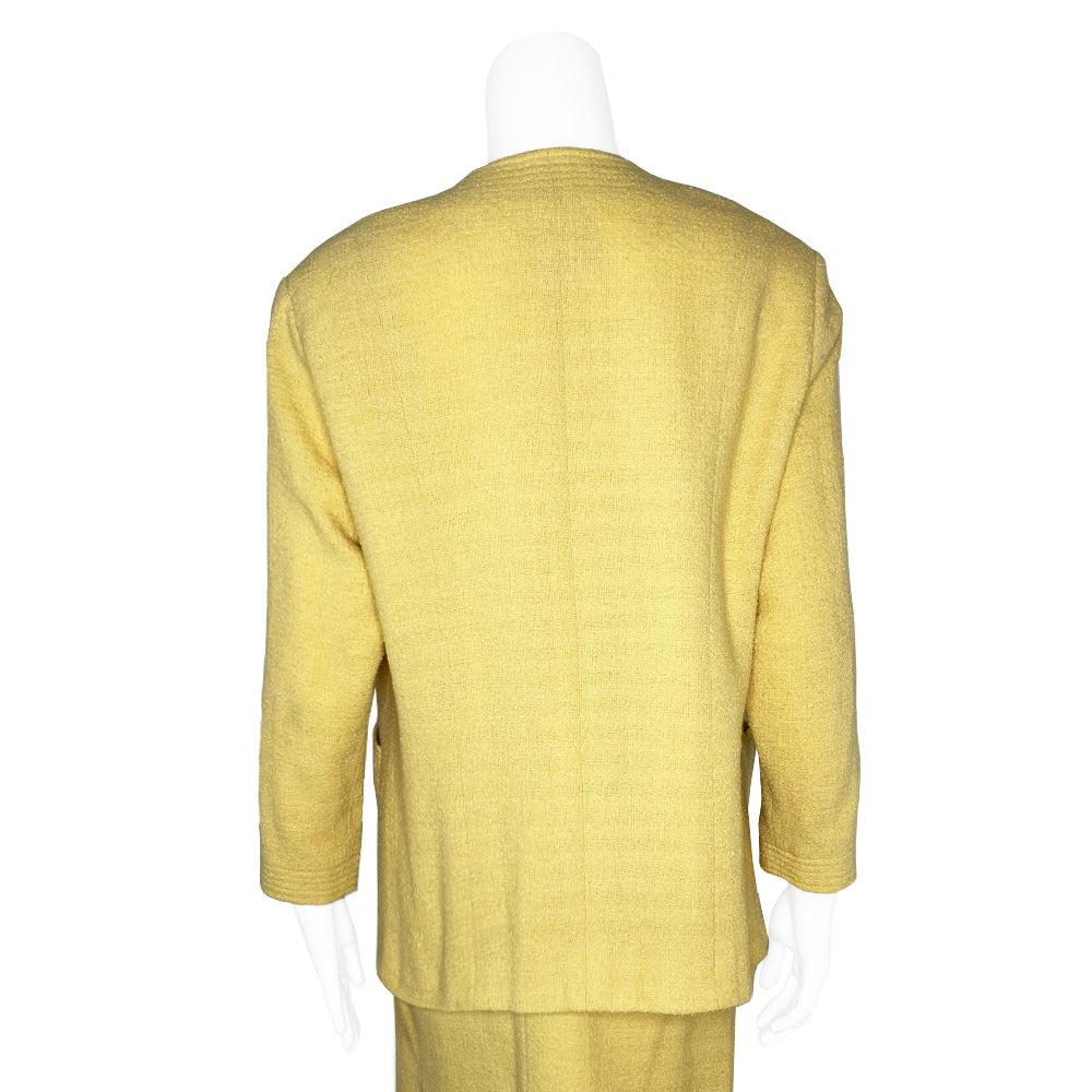 Chanel Boucle Jacket and Skirt Suit in Pale Yellow circa 1980’s in very good condition Jacket: Long sleeved with 4 pockets in front embellished with gold Chanel Rue Cambon logo buttons, 3 buttons at sleeves Skirt: Back invisible zipper with hook at waistband. Fabric: Main: 100%, Lining: 100% Silk. Made in France