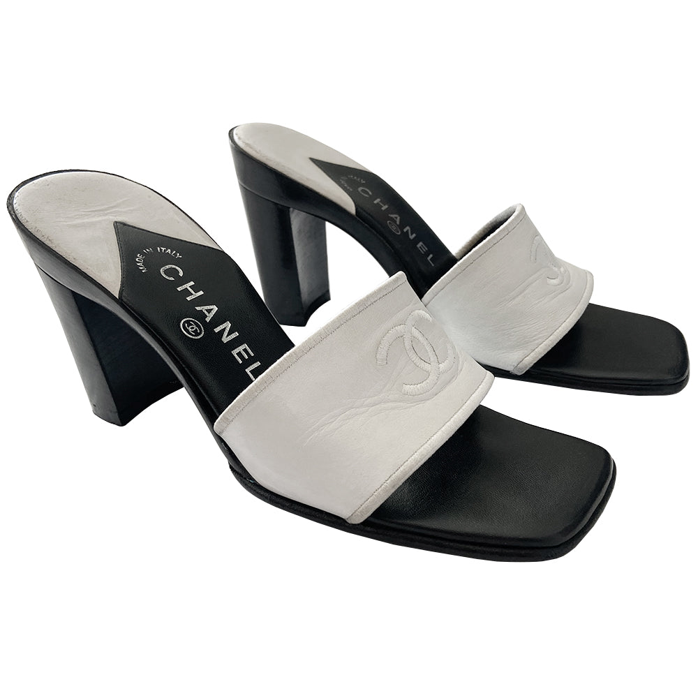Chanel white square toe slip on mules with black leather covered block heels, leather upper with embroidered interlocking CC logo and edging. White and black leather insole with leather bottom sole. Made in Italy