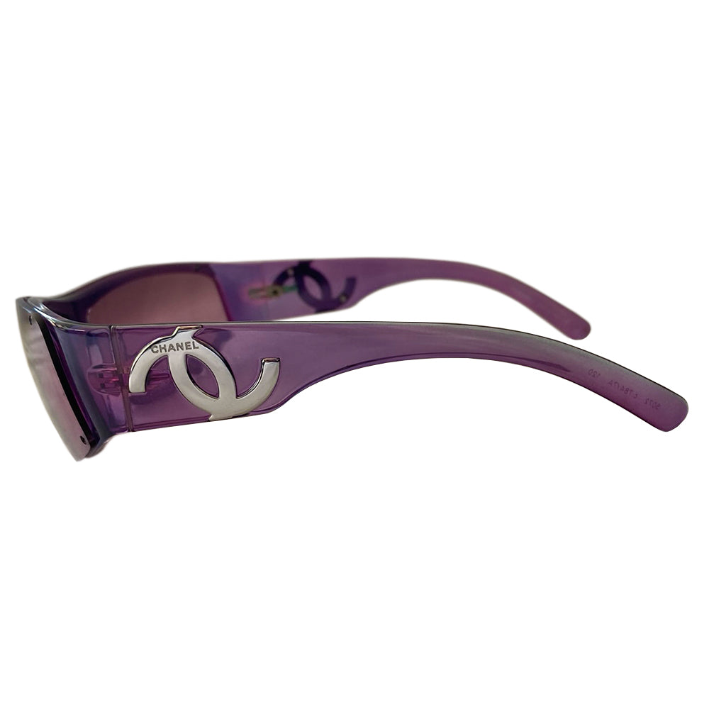 Chanel purple wrap CC logo sunglasses by Karl Lagerfeld for Chanel with frameless lens with wide purple arms and silver-tone asymmetric CC logo at temples. Style: 5072 Made in Italy