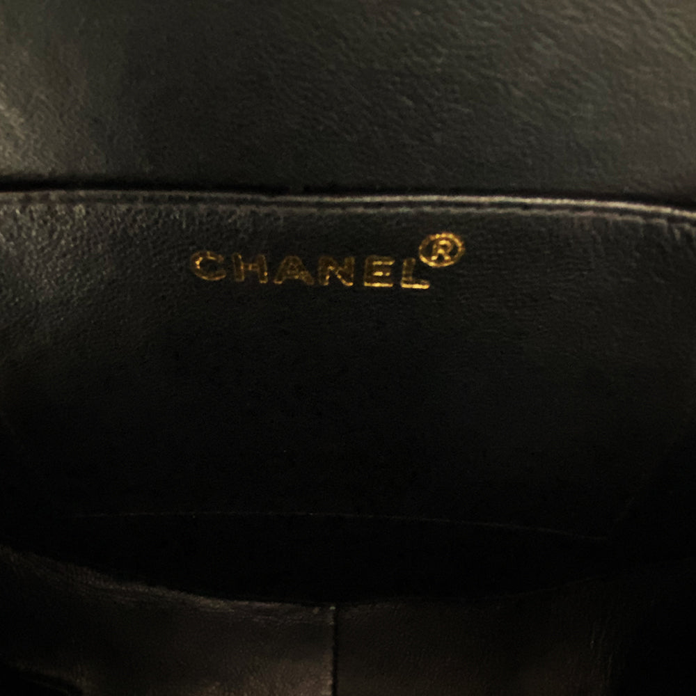 Chanel round diamond quilted black patent vanity case by Karl Lagerfeld for Chanel 1994-1996 with white interlocking appliqué CC logo at front, interwoven leather and gold chain top handle. Dual gold-tone zip around closure open to black leather interior with single slip pocket. Made in France