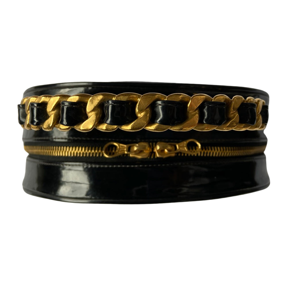 Chanel round diamond quilted black patent vanity case by Karl Lagerfeld for Chanel 1994-1996 with white interlocking appliqué CC logo at front, interwoven leather and gold chain top handle. Dual gold-tone zip around closure open to black leather interior with single slip pocket. Made in France