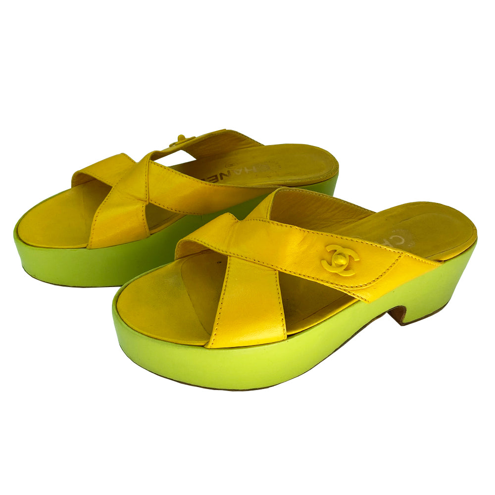 Chanel Lemon-Lime two tone lamb leather platform open toe slip on sandals circa 2002. 2” platform with small heel. Bright yellow criss-cross upper with tonal accent stitching and signature Mademoiselle lock adornment and lime green platform. Size: IT 38 Some visible scuffing. Made in Italy