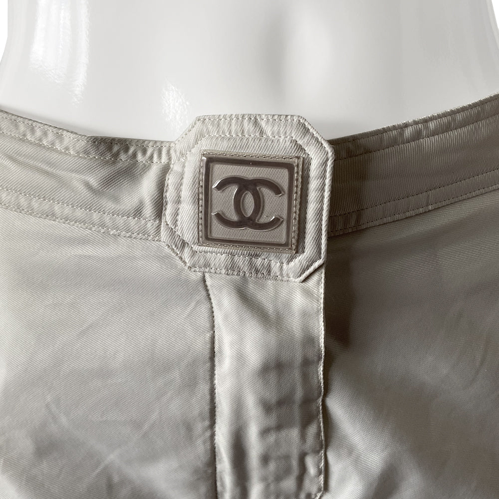 Chanel Identification white sport pants from 2001. High waisted with banded side slash pockets and back flap pockets with silver CC logo snap. Rubber identification silver and white logo at waist. Chanel logo metal toggles cinch the bottom hem. Zipper at knee removes lower leg convertible to shorts. Made in Italy