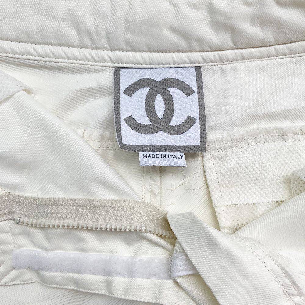 Chanel Identification white sport pants from 2001. High waisted with banded side slash pockets and back flap pockets with silver CC logo snap. Rubber identification silver and white logo at waist. Chanel logo metal toggles cinch the bottom hem. Zipper at knee removes lower leg convertible to shorts. Made in Italy