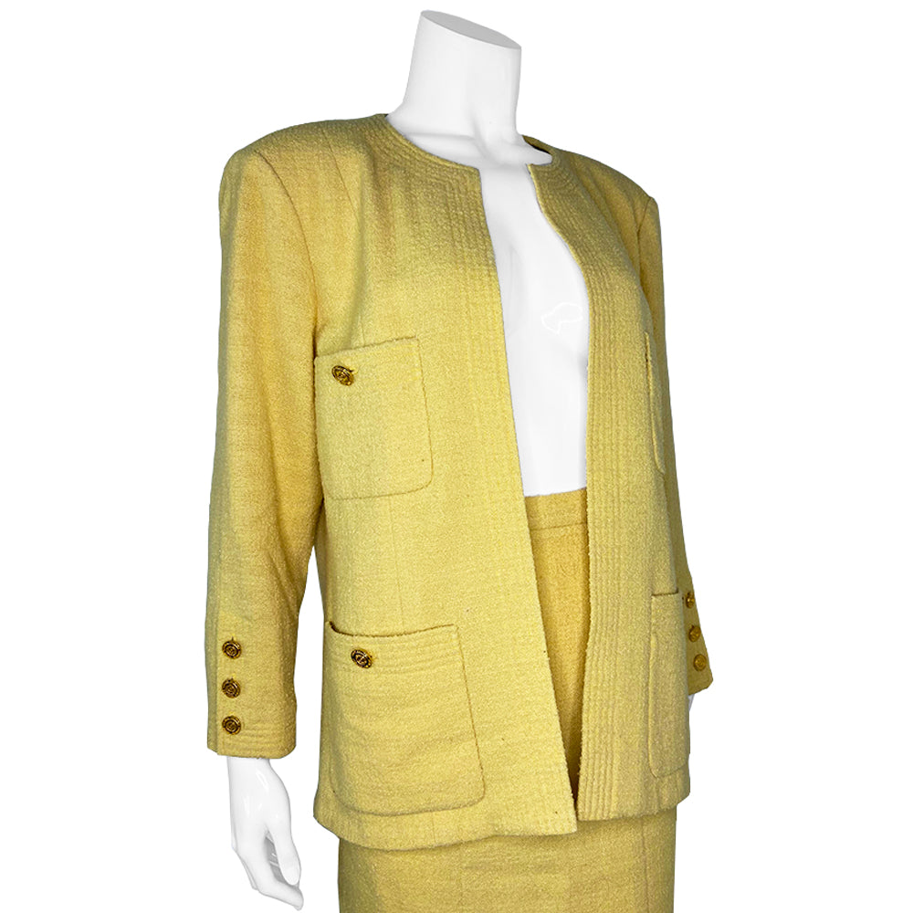 Chanel Boucle Jacket and Skirt Suit in Pale Yellow circa 1980’s in very good condition Jacket: Long sleeved with 4 pockets in front embellished with gold Chanel Rue Cambon logo buttons, 3 buttons at sleeves Skirt: Back invisible zipper with hook at waistband. Fabric: Main: 100%, Lining: 100% Silk. Made in France