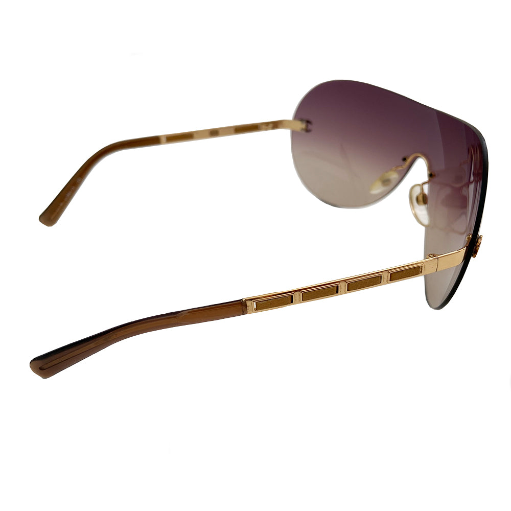 Chanel CC Leather Threaded Shield Sunglasses from mid 2000’s Oversized dark bronze gradient single shield lense and gold-tone metal arms with leather threaded through each arm. CC logo in gold on either side of frame at arm. Black quilted case included. Made in Italy.