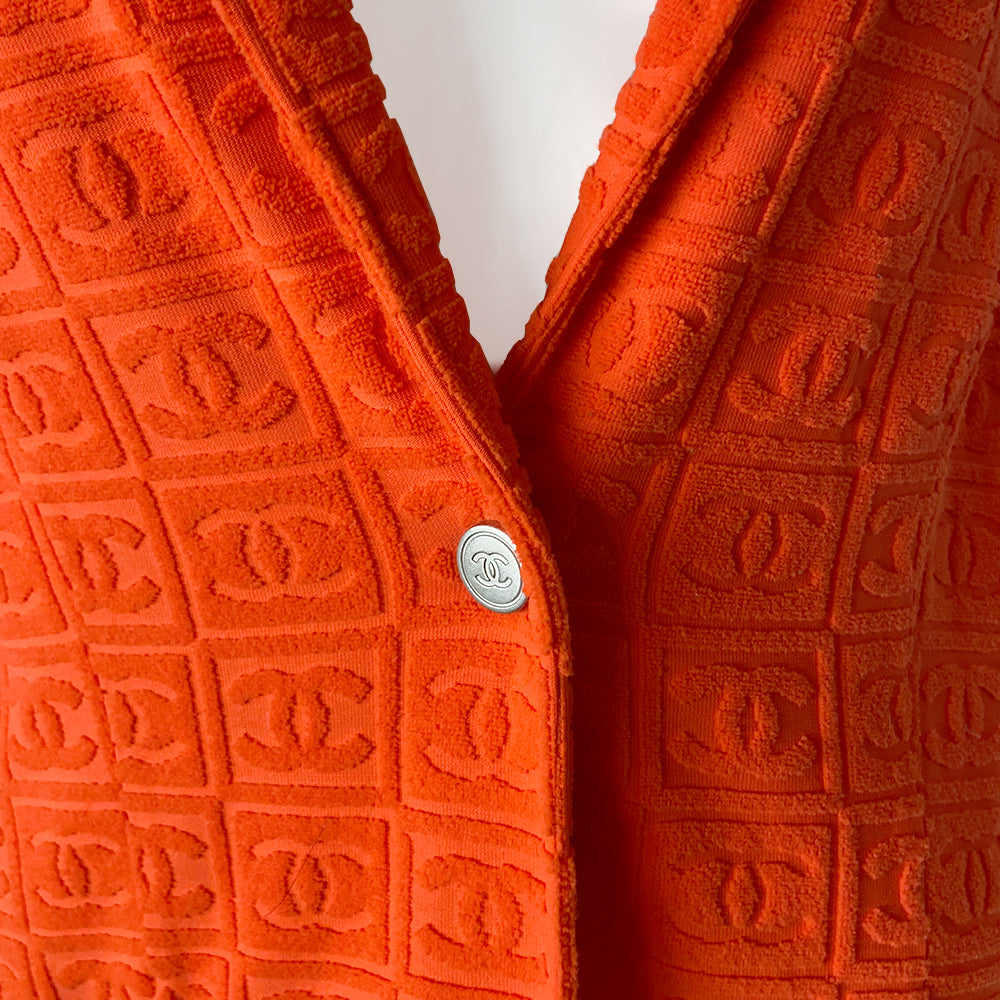 Chanel monogram terrycloth blazer by Karl Lagerfeld for Chanel S/S 2002 with long sleeves, all over boxed CC logo pattern, notched lapel, single logo silver-tone front snap button closure and 2 front patch pockets. Tangerine orange with turquoise accent. Made in France