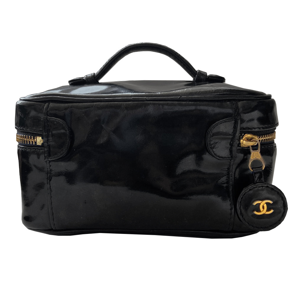 Chanel black patent leather vanity case by Karl Lagerfeld for Chanel 1996-1997 Rectangular bag with stitched interlocking CC logo at front, top handle, zip around closure with leather disc zipper pull embellished with gold CC logo. Leather interior with inner slip pocket pouch, Chanel stamped inside. Made in Italy