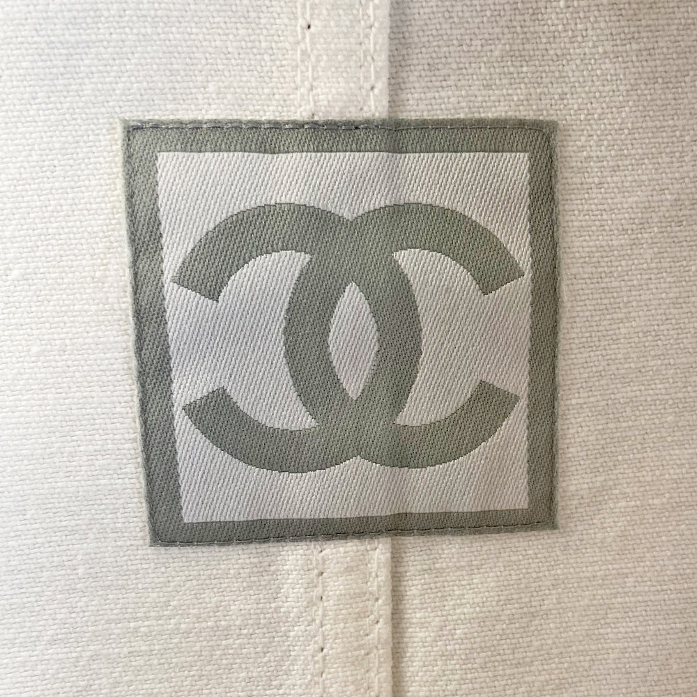 Chanel CC logo white canvas zip jacket by Karl Lagerfeld for Chanel, spring 2003 with accent stitching, brown and white striped knit accents, vented detail at sleeve hems. White CC logo zipper pull and white rubber box CC logo appliqué on arm. 100% Cotton