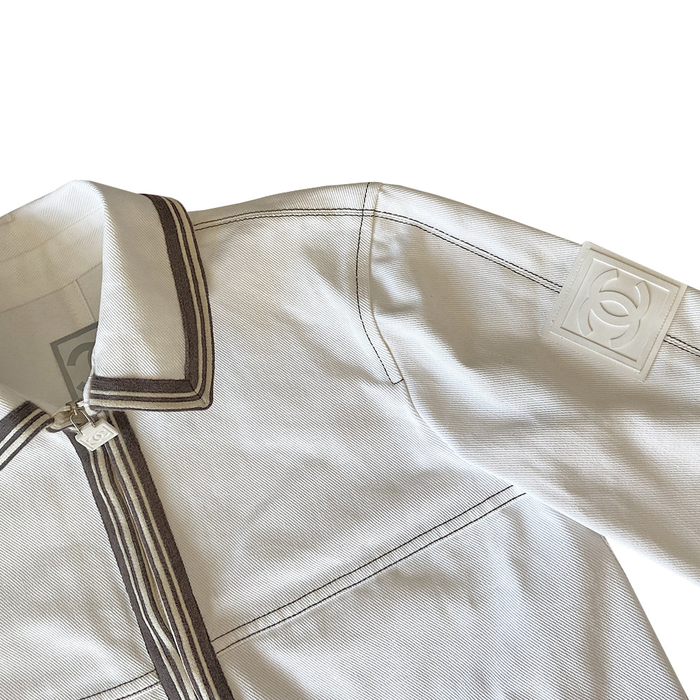 Chanel CC logo white canvas zip jacket by Karl Lagerfeld for Chanel, Cruise 2005 with accent stitching, brown and white striped knit accents, vented detail at sleeve hems. White CC logo zipper pull and white rubber box CC logo appliqué on arm. 100% Cotton