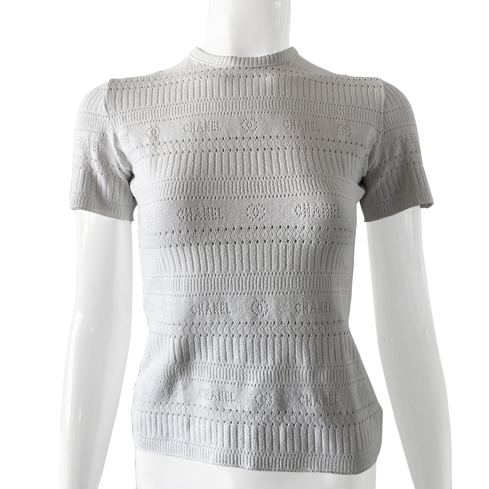 Chanel white ribbed perforated knit top by Karl Lagerfeld for Chanel, Spring 1997. Crew neck, all white short sleeved tee with perforations at ribbing edges and small woven diamond patterns to form horizontal stripes and 4 alternating rows of tiny perforations that form the word CHANEL. Made in France.
