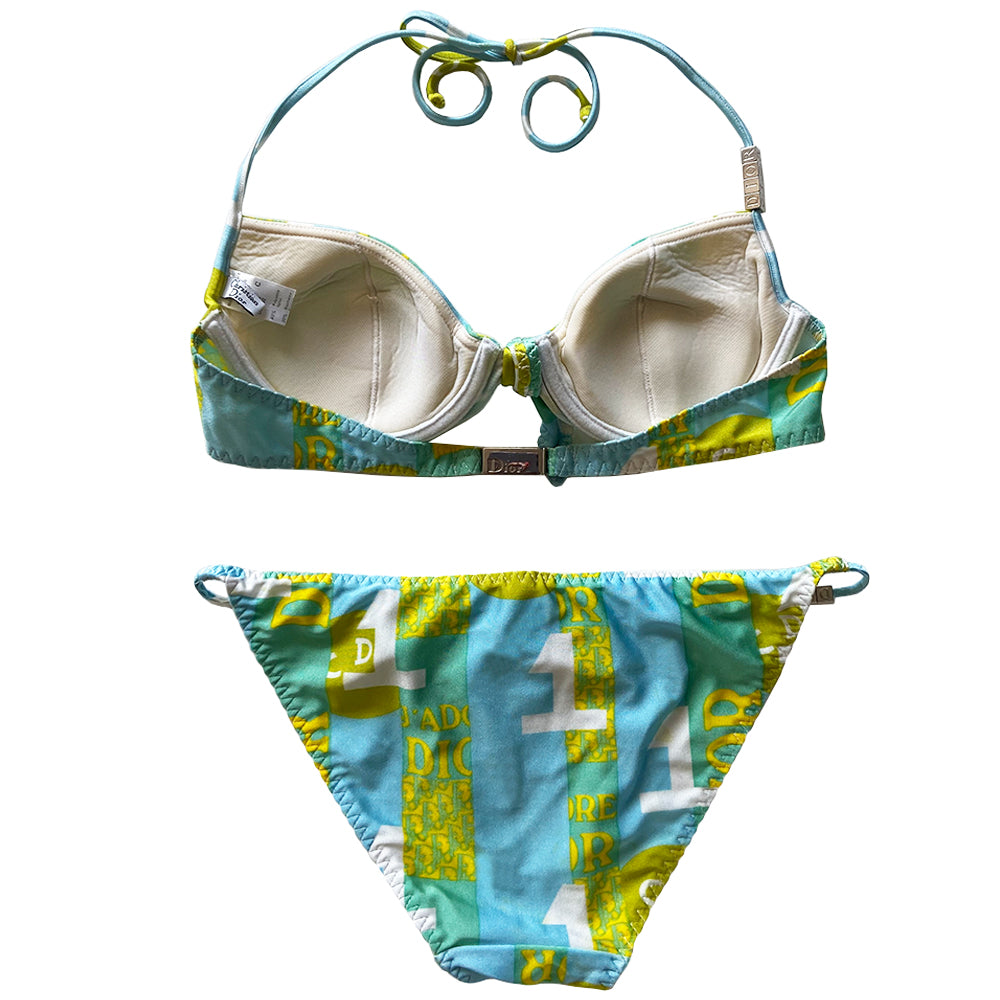 Christian Dior J’Adore Dior iconic logos bikini, spring 2005 RTW runway, John Galliano for Dior. Underwire bra with faux tie front, silver-tone engraved logo clasp back closure, ties behind the neck and silver-tone letter blocks spell out DIOR on one side. Bottoms with silver tone letter blocks spell out DIOR. Made in France