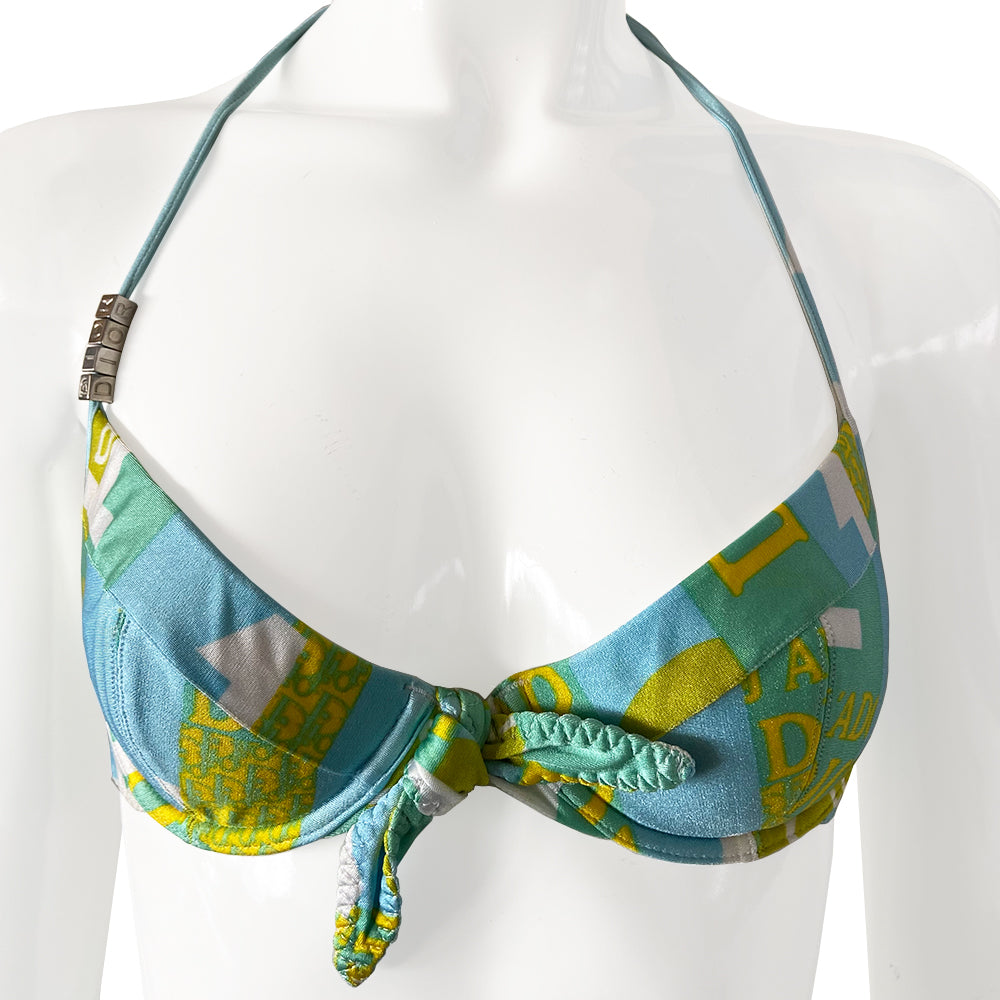 Christian Dior J’Adore Dior iconic logos bikini, spring 2005 RTW runway, John Galliano for Dior. Underwire bra with faux tie front, silver-tone engraved logo clasp back closure, ties behind the neck and silver-tone letter blocks spell out DIOR on one side. Bottoms with silver tone letter blocks spell out DIOR. Made in France