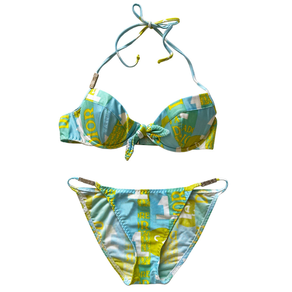 Christian Dior J’Adore Dior iconic logos bikini, spring 2005 RTW runway, John Galliano for Dior. Underwire bra with faux tie front, silver-tone engraved logo clasp back closure, ties behind the neck and silver-tone letter blocks spell out DIOR on one side. Bottoms with silver tone letter blocks spell out DIOR. Made in France