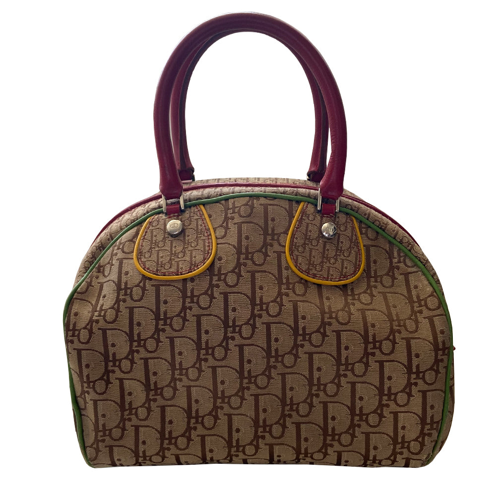 Christian Dior ad campaign Rasta Boston Bag by John Gallian for Dior. Beige and light brown Diorissimo canvas with silver-tone hardware, domed feet, 2 red leather rolled top handles, zipper pulls and end tab and red, yellow and green leather piping and tri-color leather front stripe. Made in Italy