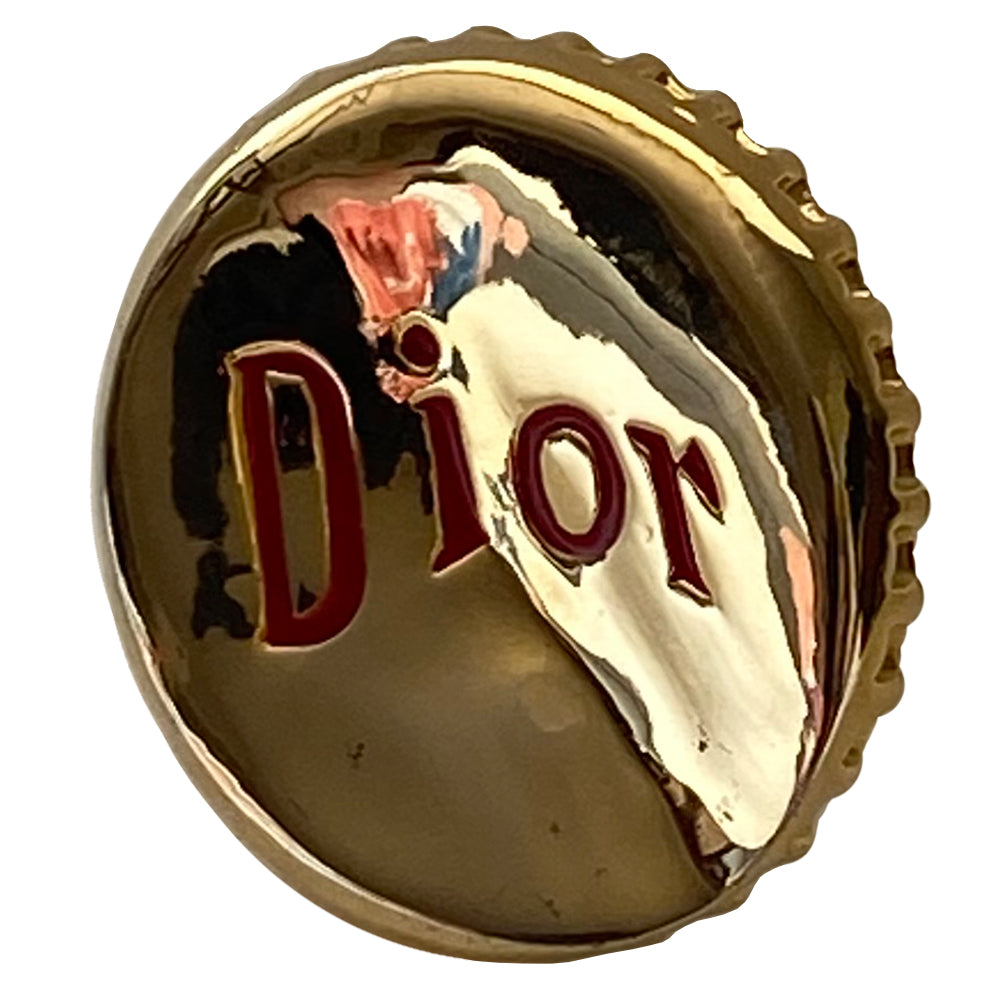 Christian Dior Logo Bottle Cap ring circa 2004. Gold-tone "bent” bottle cap ring with red embossed logo and thick band. Adjustable band for various sizing. Dior box and booklet included.