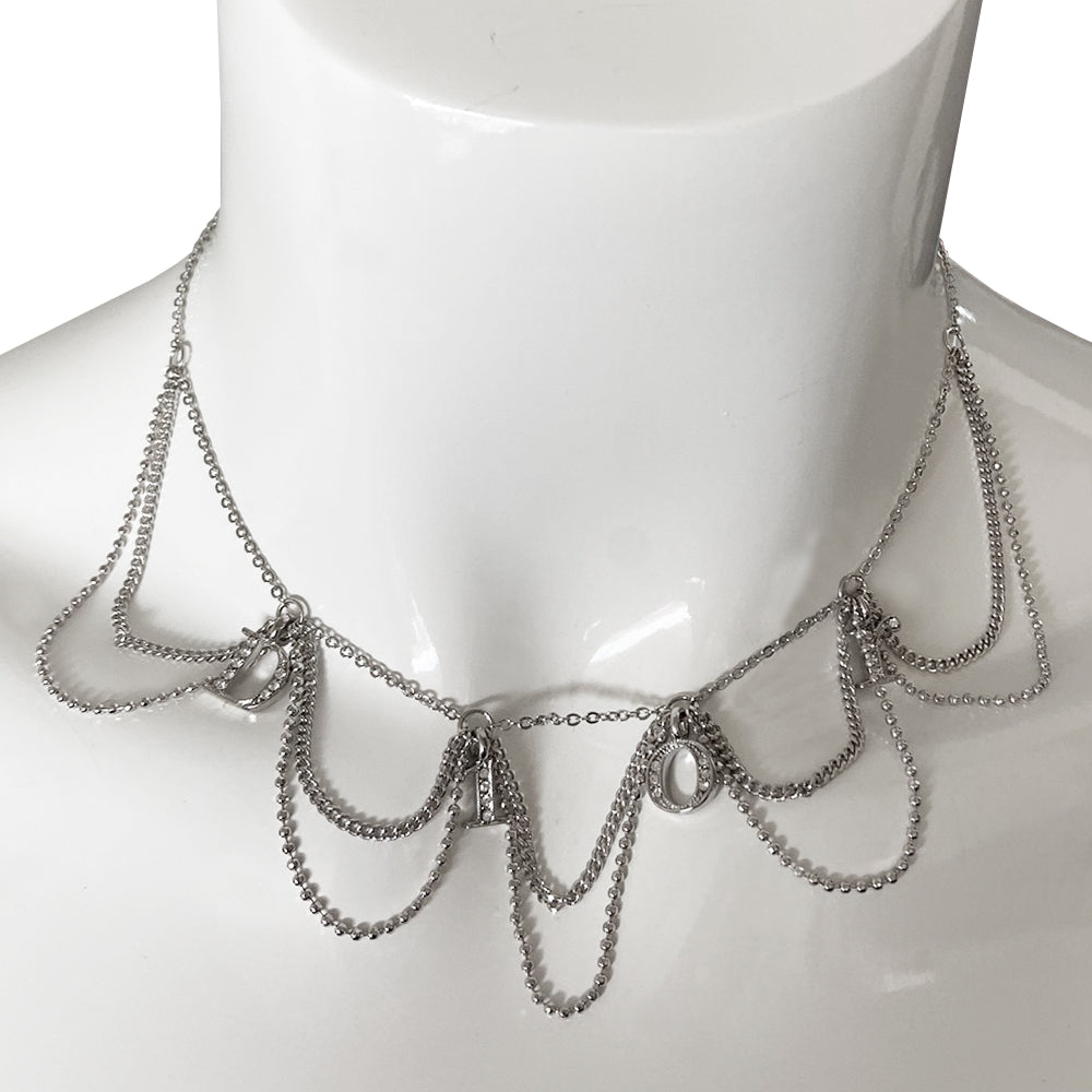 Christian Dior logo letters choker with 3 styles of draped chains and crystal embellished letters that spell Dior. Lobster back closure with 4 length adjustment loops and small hanging logo stamped D charm in back.
