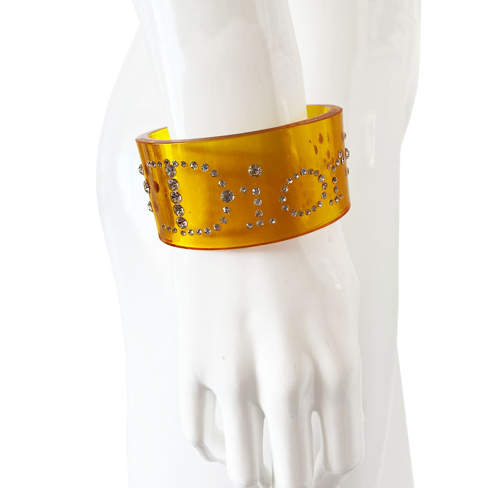 Christian Dior clear yellow lucite wide cuff bangle with Dior spelled out in white crystals.