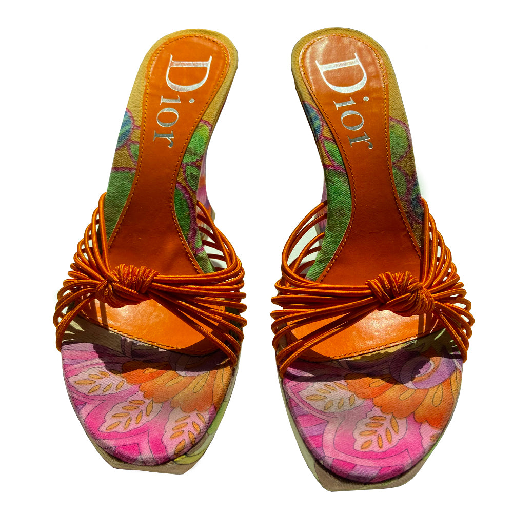 Christian Dior floral wedge platform slides circa 2002 by John Galliano for Dior. Brilliant multicolor floral fabric slip on style with 1” platform, wedge heels, leather soles and bright orange leather Dior logo insole. Multiple orange elastic cord strap upper gathered together with top knot accent. Made in Italy