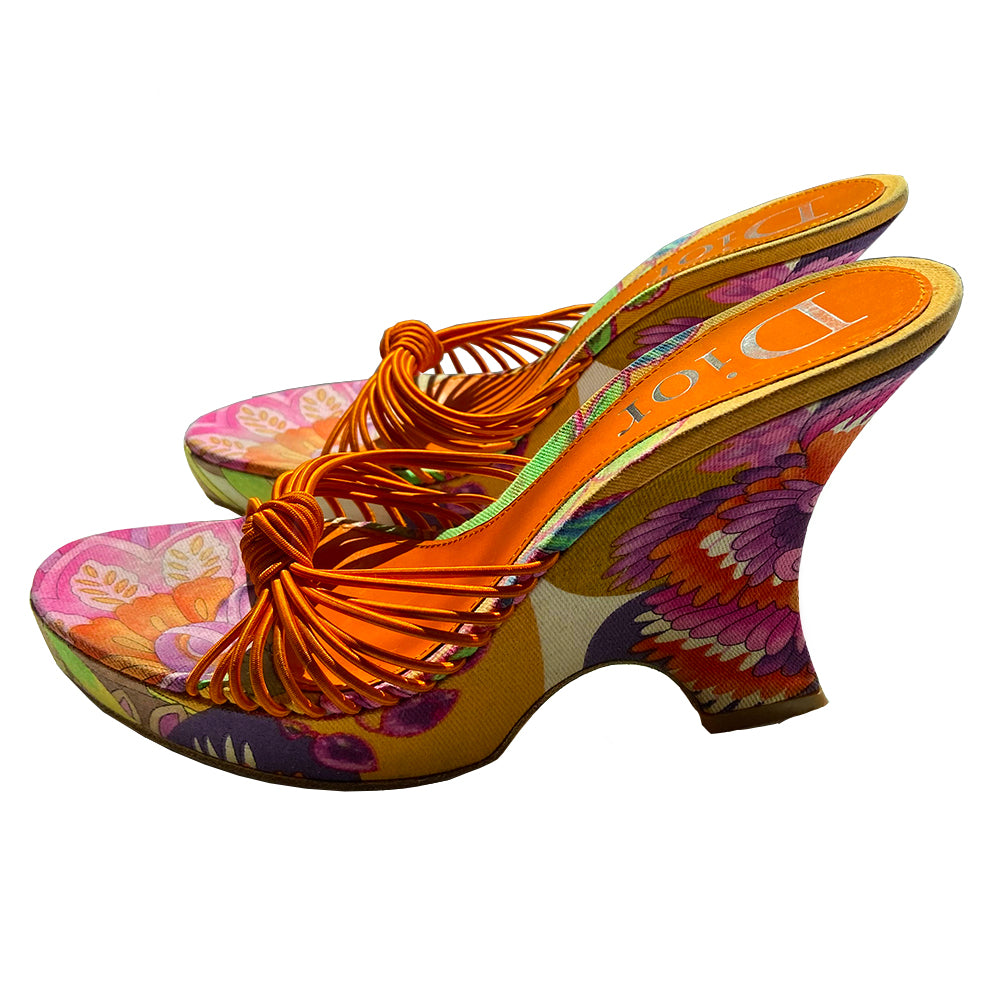 Christian Dior floral wedge platform slides circa 2002 by John Galliano for Dior. Brilliant multicolor floral fabric slip on style with 1” platform, wedge heels, leather soles and bright orange leather Dior logo insole. Multiple orange elastic cord strap upper gathered together with top knot accent. Made in Italy