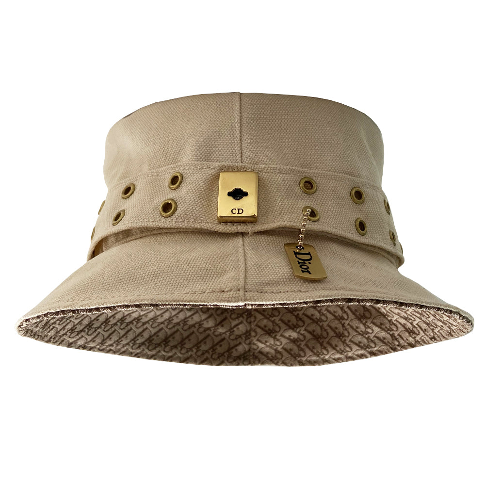 Christian Dior Street Chic Diorissimo Bucket Hat, S/S 2002 Street Chic collection by John Galliano. Light cream color canvas with tonal stitching and Diorissimo monogram logo fabric on top and under brim. Exterior band with antique brass-tone grommets and gold-tone pouch attachment and gold-tone Dior logo dog tag. Made in France