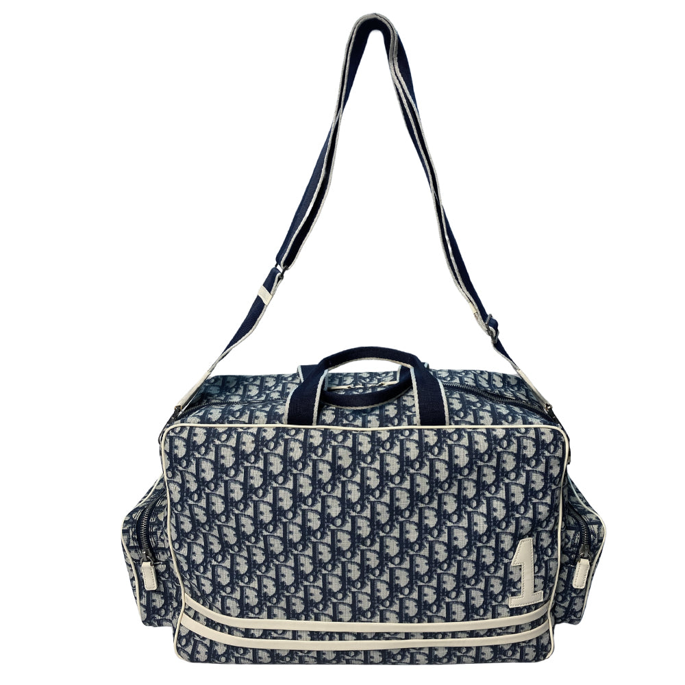 John Galliano for Dior, 2002 navy monogram canvas large weekender bag with 2 outer zip end pouches, velcro rear pocket, white patent leather piping, zipper pulls, No 1 appliqué in front and 2 accent stripes in front. Double canvas handles, detachable, adjustable navy carry strap. Silver-tone zipper and hardware, navy nylon lining with zippered pocket, two snap slip pockets, 3 open pouch pockets. Made in Italy