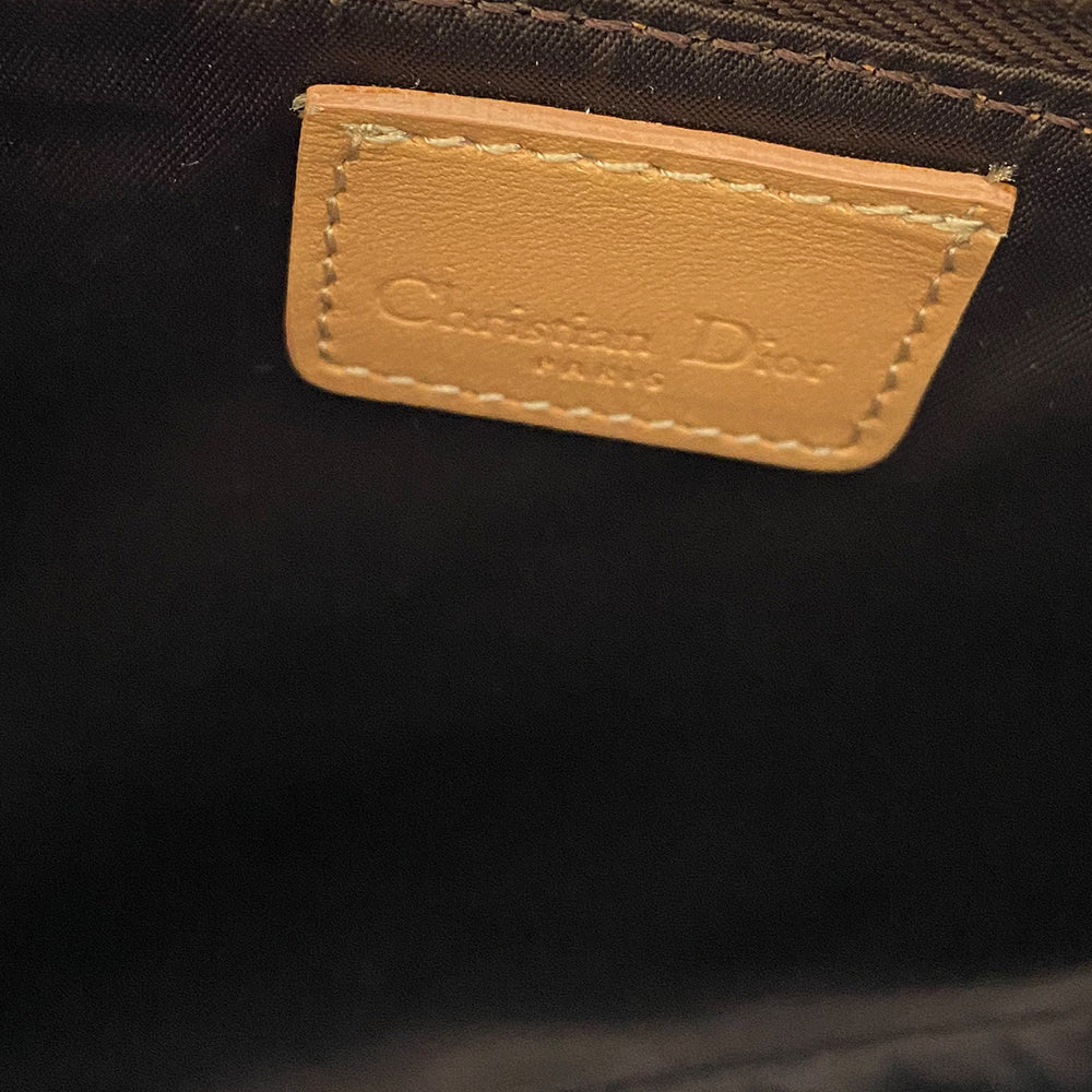 Christian Dior brown monogram canvas mini saddle pochette by John Galliano for Dior, 2001 with tan leather piping and strap with gold-tone hardware. Leather strap unclips at one end and can be looped to carry wristlet style. Top zip closure with Dior embossed leather zipper pull, brown textile interior. Made in Spain