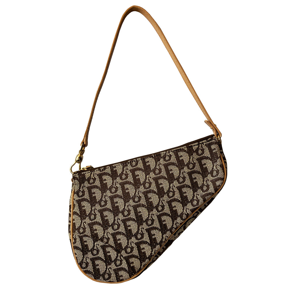 Christian Dior brown monogram canvas mini saddle pochette by John Galliano for Dior, 2001 with tan leather piping and strap with gold-tone hardware. Leather strap unclips at one end and can be looped to carry wristlet style. Top zip closure with Dior embossed leather zipper pull, brown textile interior. Made in Spain