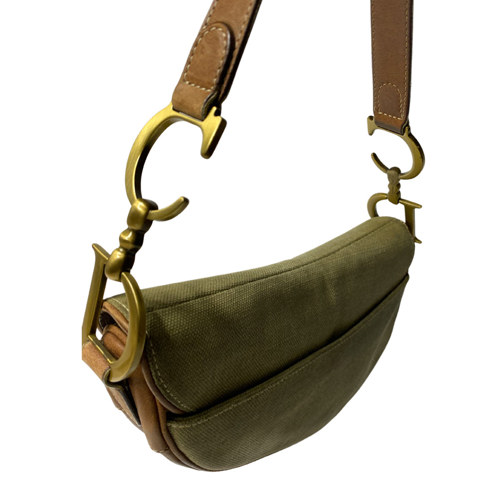 Christian Dior khaki canvas saddle bag by John Galliano for Dior 2002 with burnished gold-tone hardware, brown leather accent. Single flat top leather handle with CD logo adornments at each side. Velcro at flap closure with feature gold-tone D logo. Rear single slip pocket. Black/grey logo textile lined with zip pocket. Made in Italy