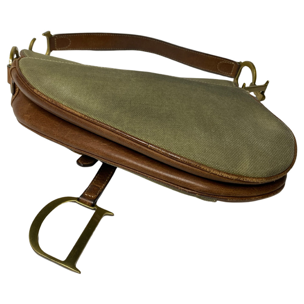 Christian Dior khaki canvas saddle bag by John Galliano for Dior 2002 with burnished gold-tone hardware, brown leather accent. Single flat top leather handle with CD logo adornments at each side. Velcro at flap closure with feature gold-tone D logo. Rear single slip pocket. Black/grey logo textile lined with zip pocket. Made in Italy